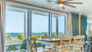 A dining area with a view of the ocean, a ceiling fan, and a wooden table with chairs. - Piece of Paradise located at Hawks Cay in Duck Key (Duck Key)