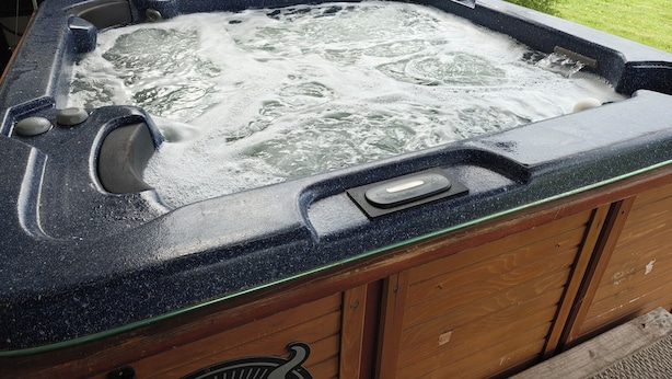 A hot tub with a control panel and a wooden cabinet. - Charming Home with private Hot Tub and Fire Pit (South Point)