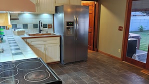 A kitchen with a stainless steel refrigerator, a built-in oven, and a tiled backsplash. - Charming Home with private Hot Tub and Fire Pit (South Point)
