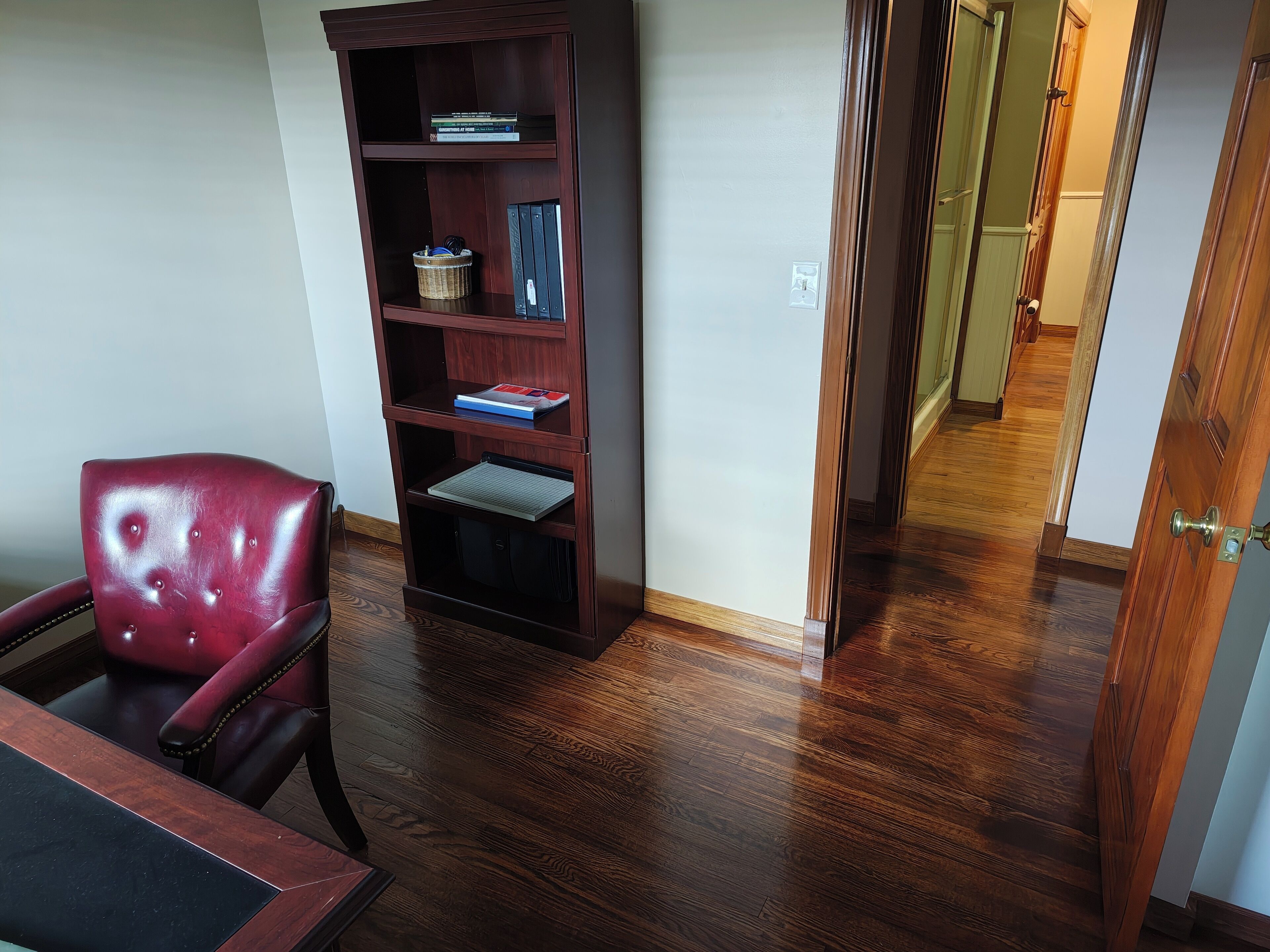 Ein Zimmer mit einer dunklen Holzhülle, einem roten Ledersessel und einem Holztisch.
