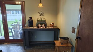 A kitchen with a coffee station, a wooden table, and a door. - Charming Home with private Hot Tub and Fire Pit (South Point)