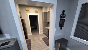 Une cuisine moderne avec un plancher en bois, un réfrigérateur en acier inoxydable et un panneau fixé au mur indiquant que la cuisine est ouverte.