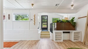 A spacious hallway with a wooden floor, white walls, and a staircase leading to a second floor.