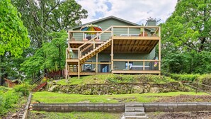 A two-story house with a wooden deck and a staircase leading to a balcony.