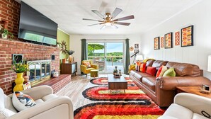 A living room with a brick fireplace, leather sofa, and a colorful rug.