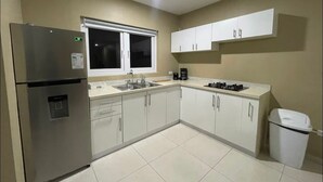 A kitchen with a refrigerator, sink, cabinets, and a window. - Island Escape Home in Noord, Aruba (Noord)