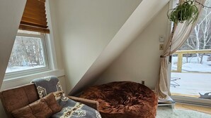 A cozy room with a brown sofa, a large brown bean bag, and a white furry rug. - Cozy cabin >> Hottub, WiFi, AC. Easy access to outdoors activities year around (Hancock)