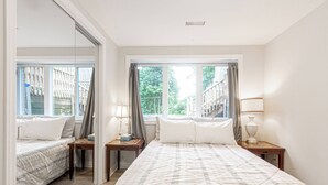 Une chambre avec deux lits, un miroir et une fenêtre avec des rideaux.
