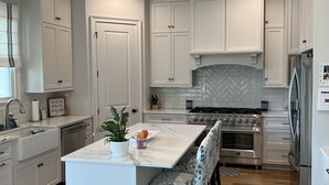 A modern kitchen with white cabinetry, a central island, and a built-in oven.