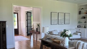 A spacious living room with hardwood flooring, a central coffee table, and a seating area with a sofa and armchairs.