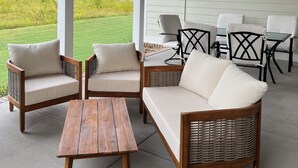 A covered outdoor seating area with wicker furniture and a ceiling fan.