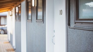 A row of hotel doors with numbers, a wooden ceiling, and a window. - The Turoa Lodge Ohakune (Ohakune)