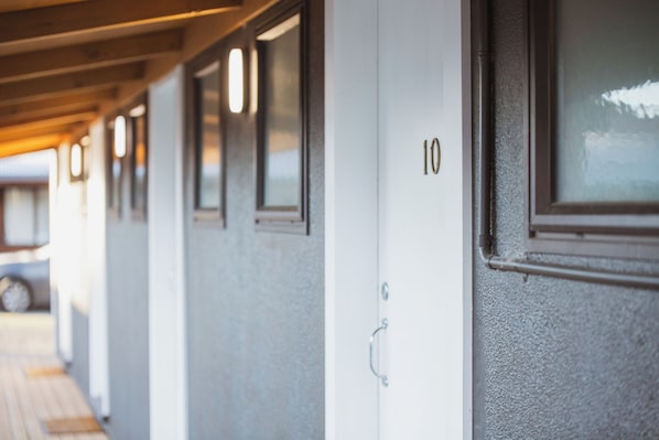 A row of hotel doors with numbers, a wooden ceiling, and a window.