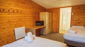 A wooden cabin room with two beds, a TV on a desk, and a wardrobe. - The Turoa Lodge Ohakune (Ohakune)