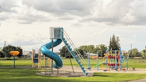 A playground with a blue slide and various play structures. - Teton Heritage House | Yellowstone Central Hub | Magical Tree (Teton)