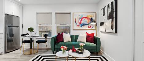 Una sala de estar moderna con un sofá verde, dos mesas redondas blancas y un tapete a rayas negras y blancas.
