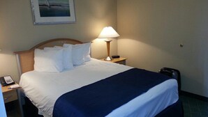 A hotel room with a neatly made bed, a bedside lamp, a phone, and a suitcase. - Week long hotel suite unit at Wyndham Inn on the Harbor in Newport (Newport)