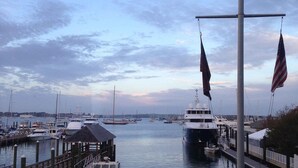 A marina with boats docked, a wooden pier, and a flagpole with flags. - Week long hotel suite unit at Wyndham Inn on the Harbor in Newport (Newport)