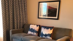 A living room with a sofa, two pillows, a wooden coffee table, and a framed picture on the wall. - Week long hotel suite unit at Wyndham Inn on the Harbor in Newport (Newport)