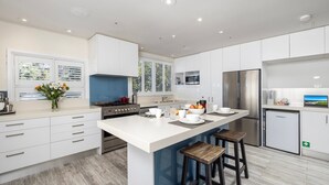A modern kitchen with white cabinetry, a central island, and a stainless steel refrigerator.
