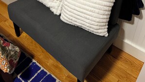 A small, dark grey sofa with a white, textured throw blanket and a dark blue blanket draped over it. - Charming, private 3BR cottage with WiFi, A/C, full washer & dryer in Oakland (Oakland)