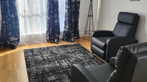 Una sala de estar moderna con un sofá de cuero negro, una alfombra negra y una lámpara de pie.