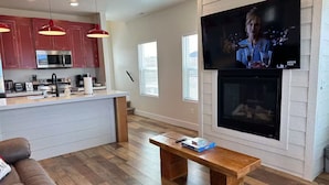A modern living room with a wooden floor, a sofa, a coffee table, and a TV mounted on the wall.