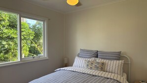 Une chambre à coucher avec un lit, une table de chevet, une lampe et un ventilateur de plafond.