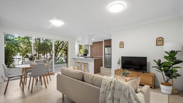 A modern living room with a sofa, TV, and dining area.