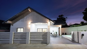 A modern house with a covered patio, a fenced front yard, and a pool area. - Villa Anna (Pattaya)