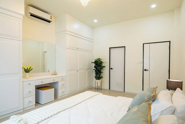 Une chambre à coucher comprenant un lit, une commode, un miroir, une plante en pot et deux portes.