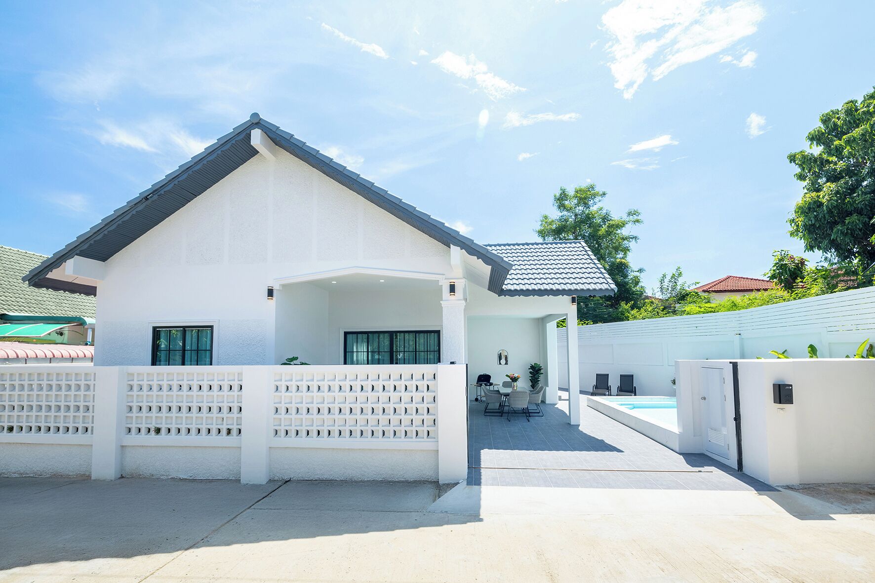 Ein modernes Haus mit überdachter Terrasse, Schwimmbad und geschlossenem Eingang.