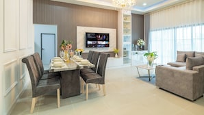 A modern living room with a dining area, a sofa, and a TV mounted on the wall. - Villa Anna (Pattaya)