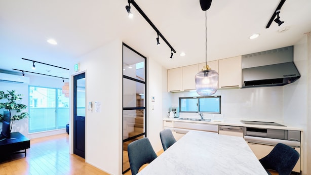 A modern kitchen with a large island, built-in appliances, and a dining area with a marble table.