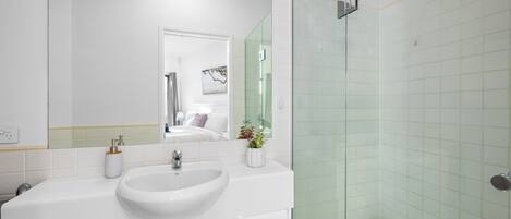 A modern bathroom with a white sink, a large mirror, and a glass shower enclosure.