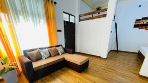 Een moderne woonkamer met een hoekbank, houten vloeren en een potplant.