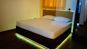 Een bed met houten frame en hoofdbord met LED-verlichting, een effen wand en een houten vloer.