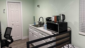 Una cucina compatta con forno a microonde, macchina del caffè e lavello.