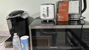 Un angolo cottura con macchina da caffè Keurig, un tostapane bianco, una cialda di caffè Pike Place Roast, una caffettiera e una bottiglia d'acqua.