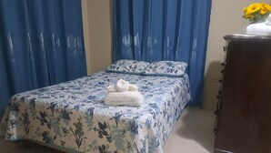 Una cama bien hecha con una colcha estampada, una toalla doblada y almohadas a juego.