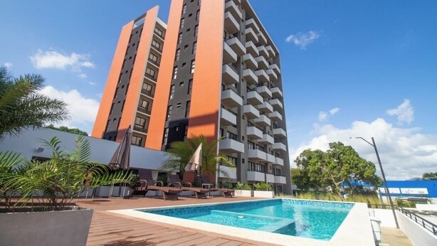 A high-rise hotel with a swimming pool and outdoor seating area.