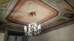 A room with a decorative ceiling featuring geometric patterns and a chandelier with multiple lights.