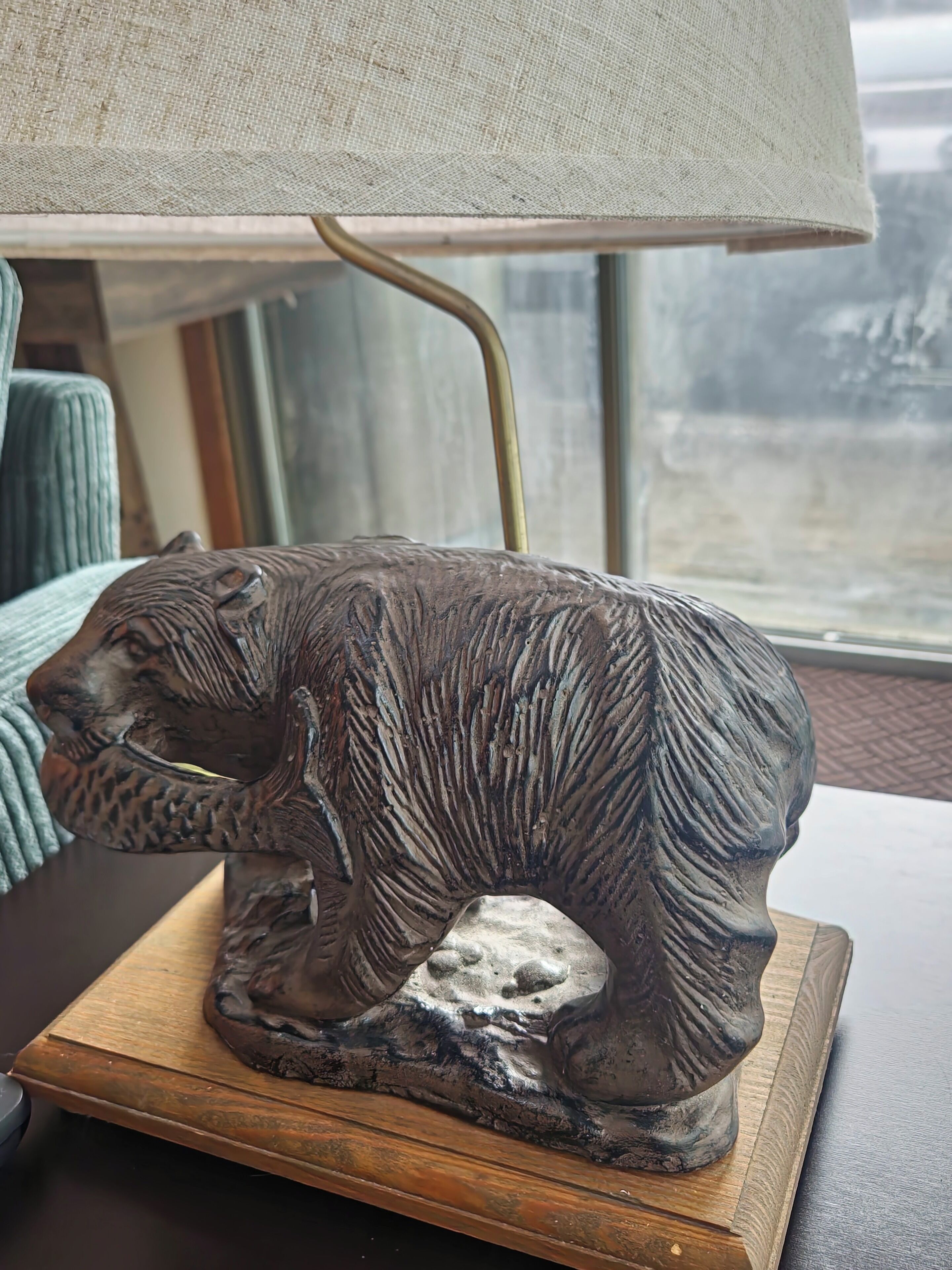 A bear-shaped lamp on a wooden table with a window in the background.