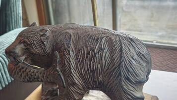A bear-shaped lamp on a wooden table with a window in the background.