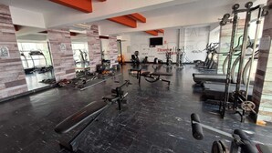 A gym with various exercise equipment, mirrors, and a large mirror reflecting the gym area.