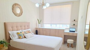 A modern bedroom with a large bed, a desk, and a laptop.
