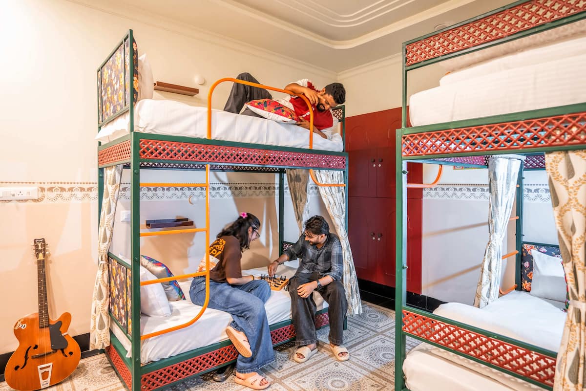 A dormitory room with bunk beds, a guitar, and a chessboard.