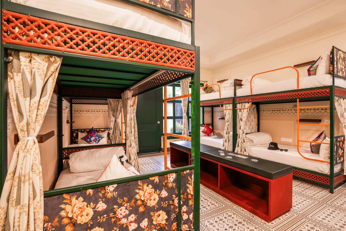 A room with two bunk beds, a small table, and a window with curtains.