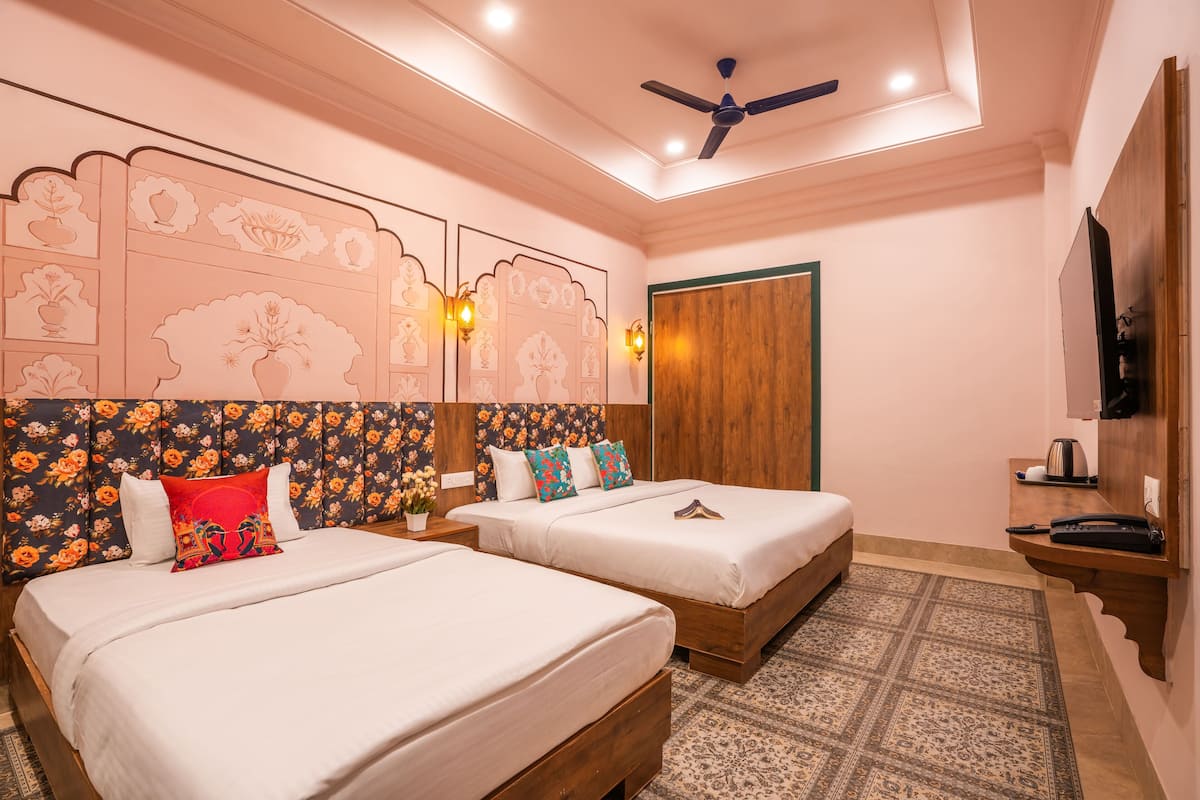 A hotel room with two beds, a ceiling fan, a TV, and a wooden side table.