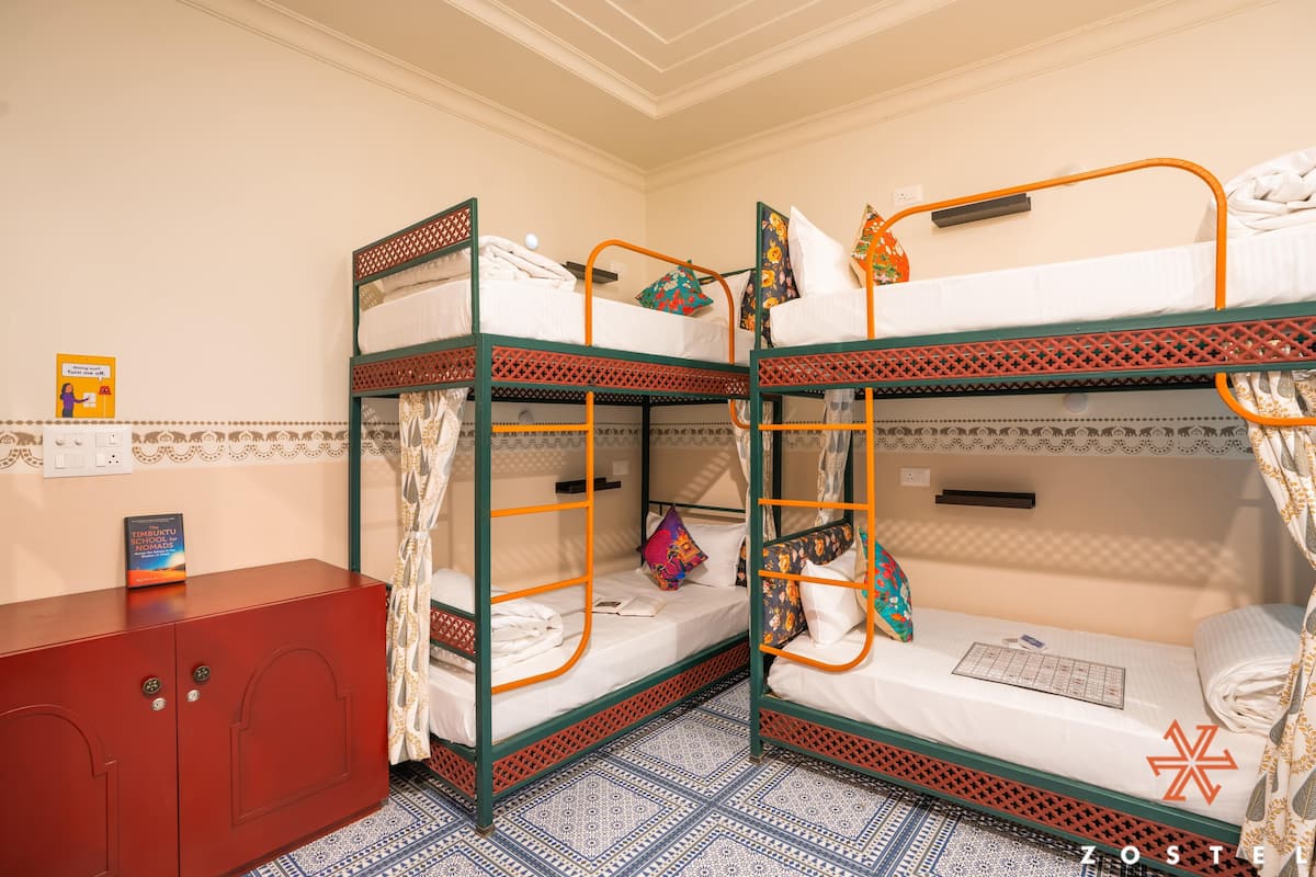 A dormitory room with bunk beds, a red cabinet, and patterned floor tiles.